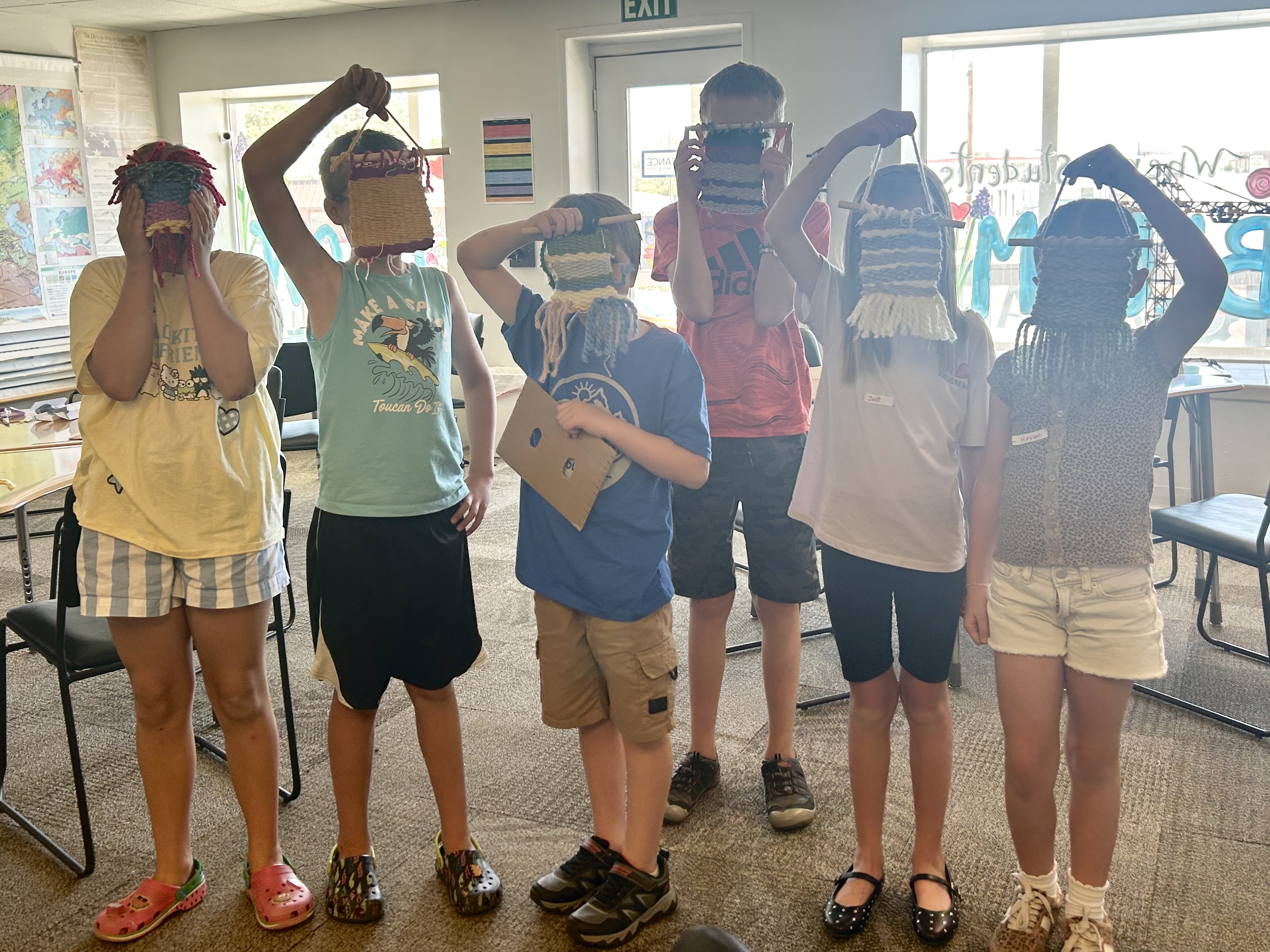 Campers holding up their finished weavings