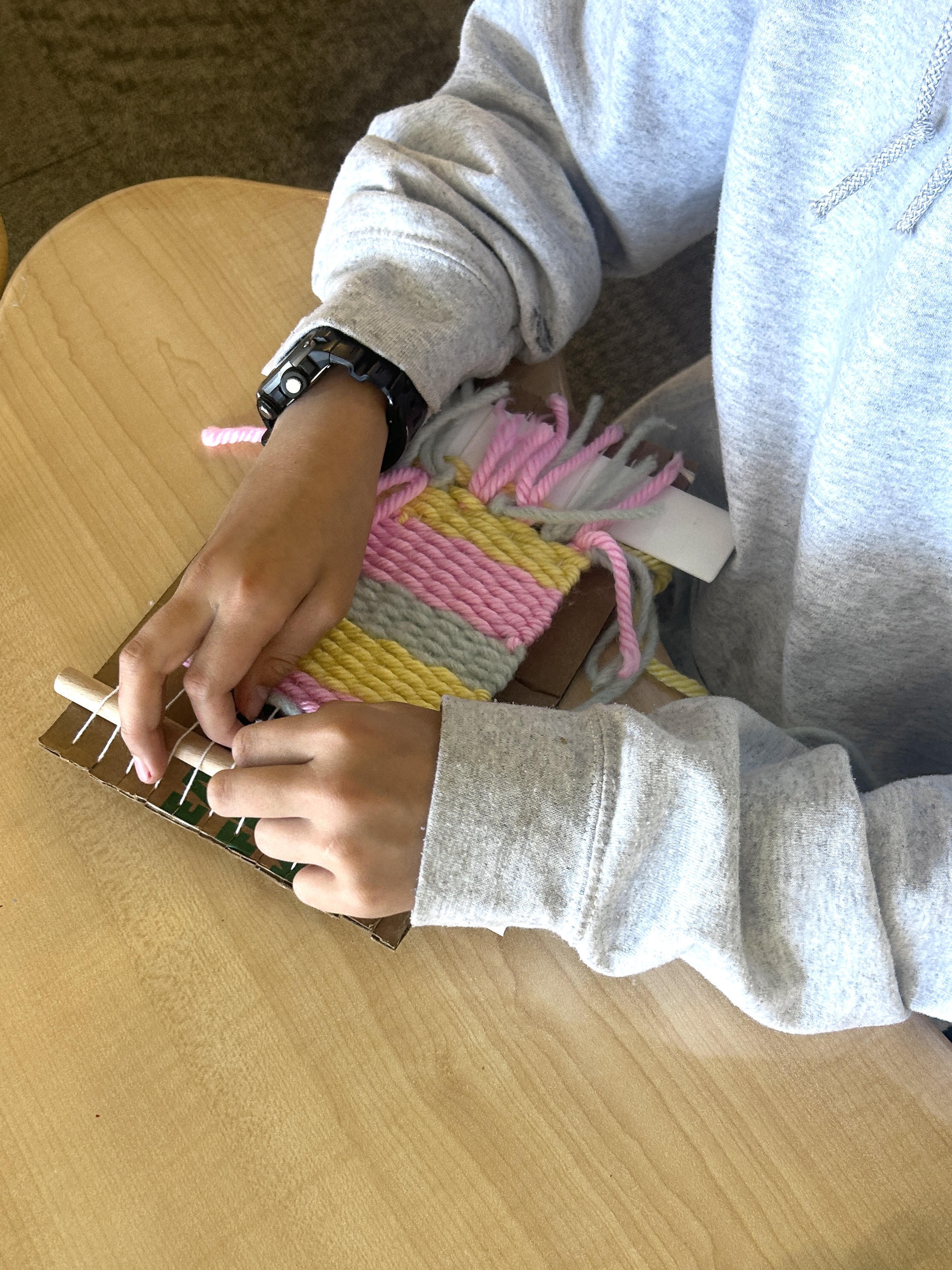 Student weaving on a cardboard loom