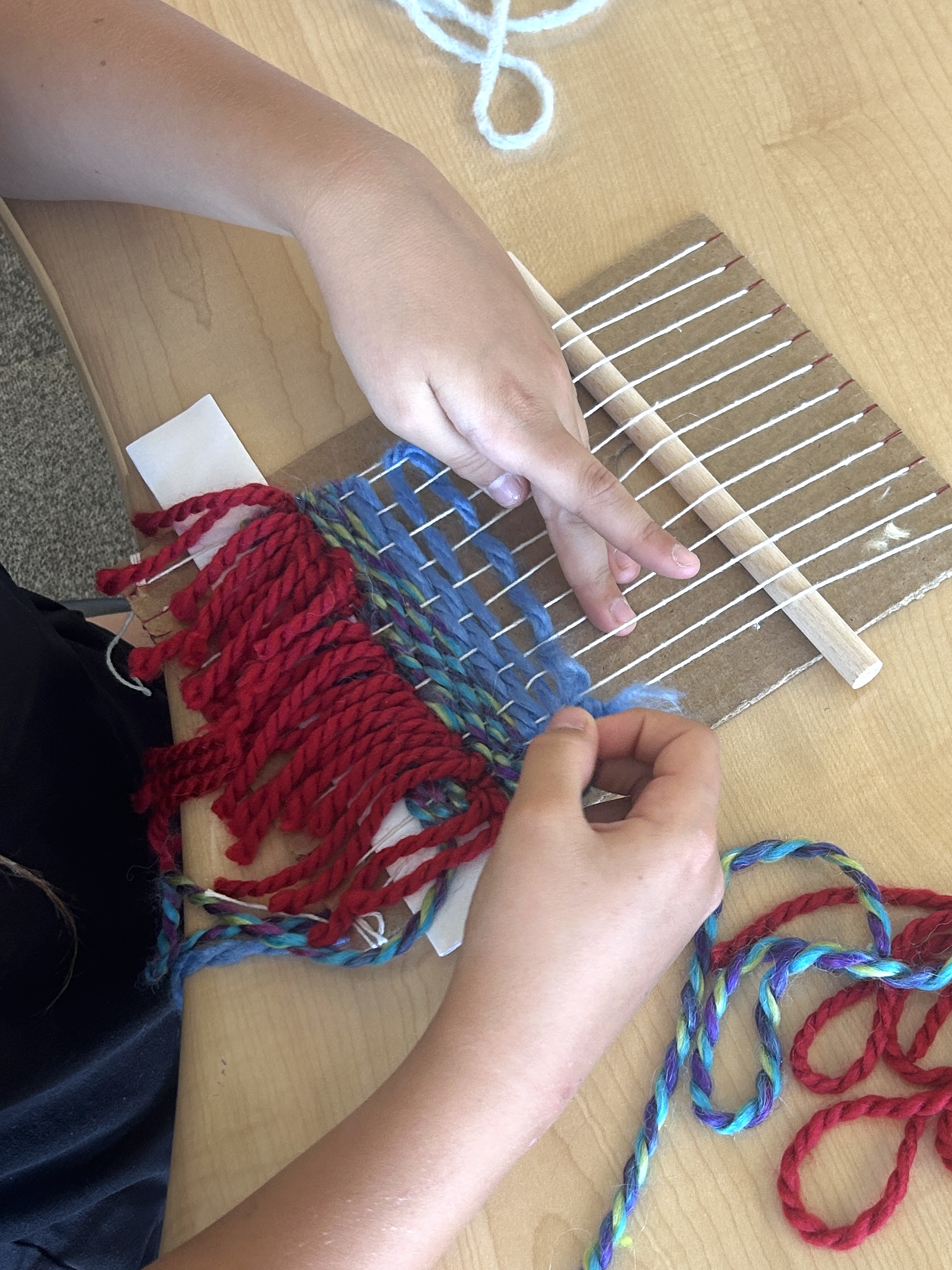 Student weaving with red and blue yarn